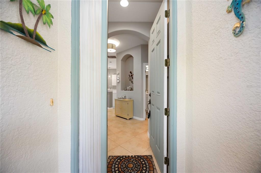 A view through an open doorway into a tiled entryway with an arched wall niche — 242 MESTRE PLACE, NOKOMIS, FL
