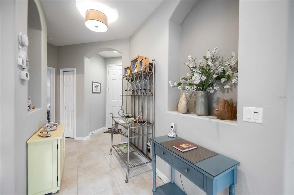 A hallway features tile flooring, a metal wine rack, and a blue console table — 242 MESTRE PLACE, NOKOMIS, FL