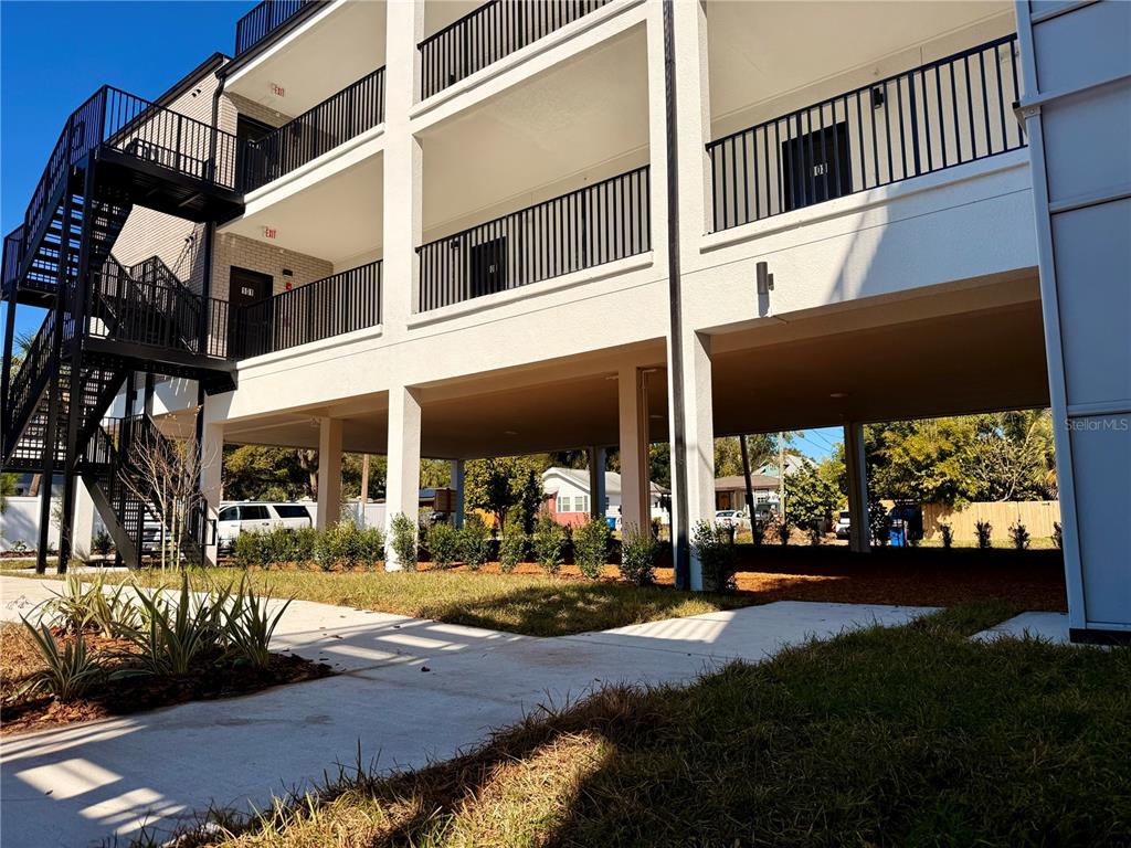A multi-story apartment building features exterior staircases, balconies with black railings, and covered parking underneath — 3601 6TH STREET S, ST PETERSBURG, FL