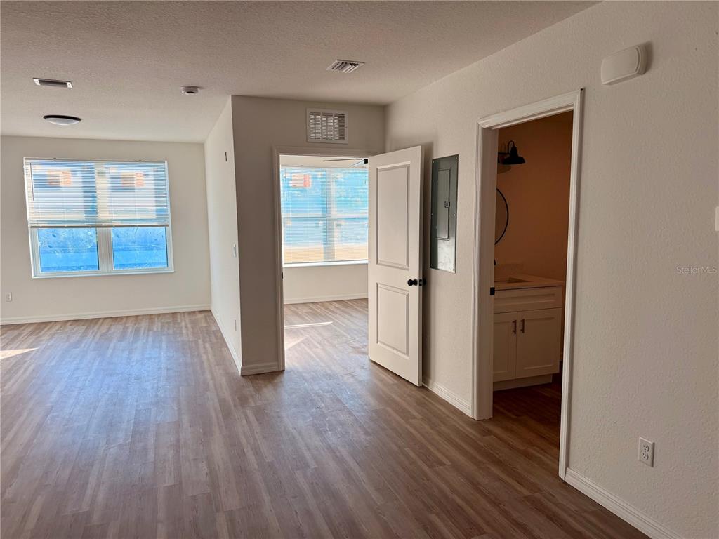 An interior view shows a living area with wood-look flooring, a bedroom doorway, and a bathroom — 3601 6TH STREET S, ST PETERSBURG, FL