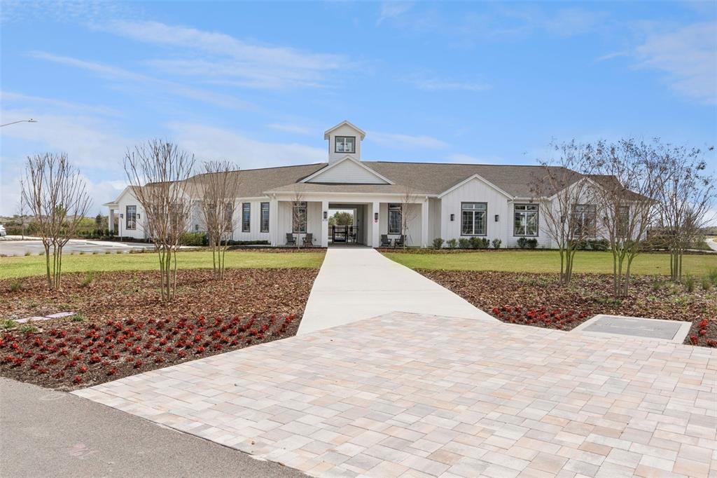 A white farmhouse-style building with a cupola sits behind a paved walkway and landscaping — 5360 CLOUDBERRY AVENUE, LAKELAND, FL