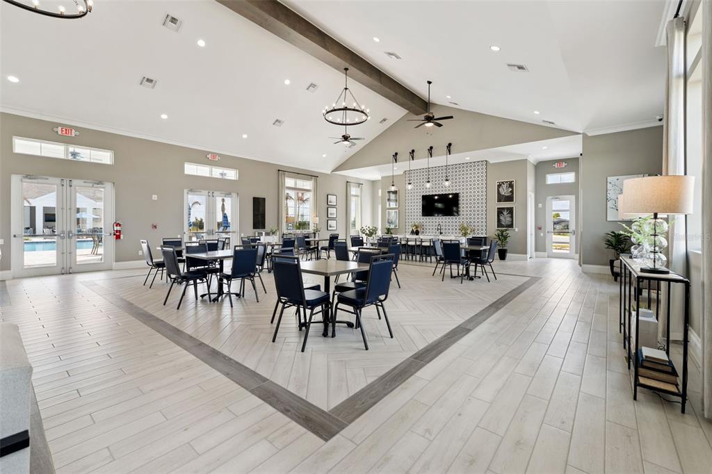 A spacious community room features a vaulted ceiling, herringbone tile floors, and multiple dining tables — 5360 CLOUDBERRY AVENUE, LAKELAND, FL