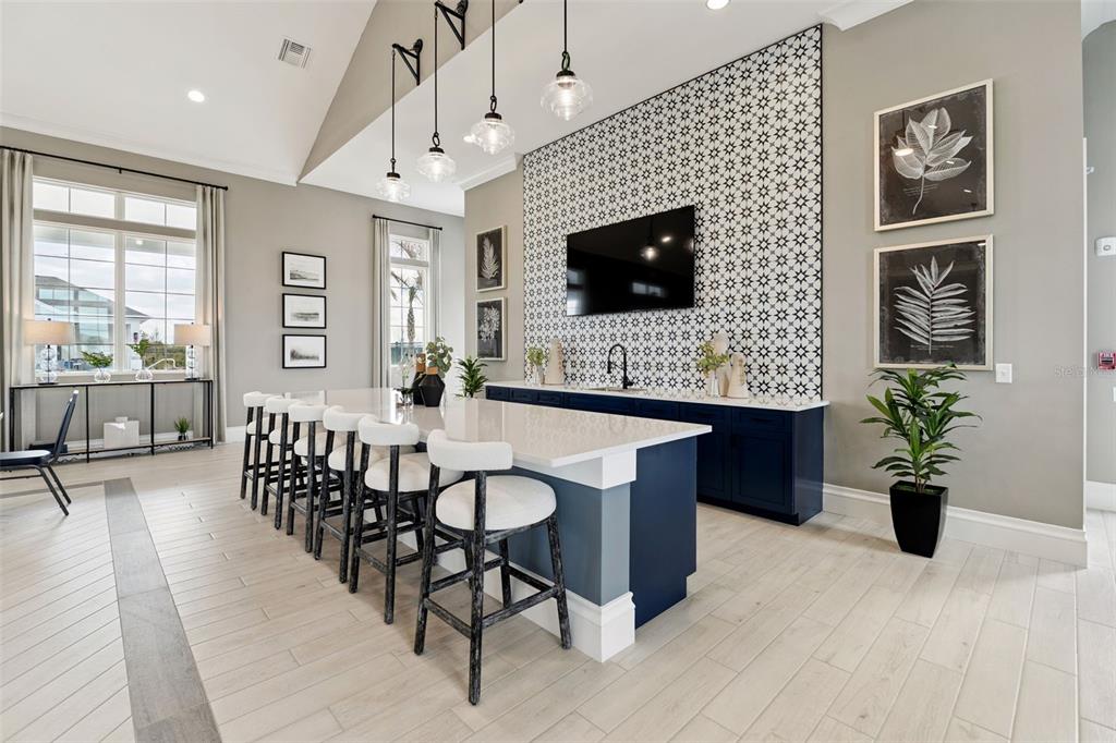 A modern kitchen features a large island with bar seating and a patterned tile backsplash — 5360 CLOUDBERRY AVENUE, LAKELAND, FL