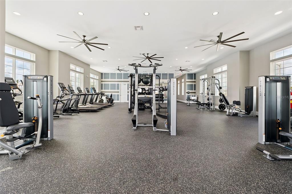 A spacious fitness center features various Matrix exercise machines, ceiling fans, and rubber flooring — 5360 CLOUDBERRY AVENUE, LAKELAND, FL