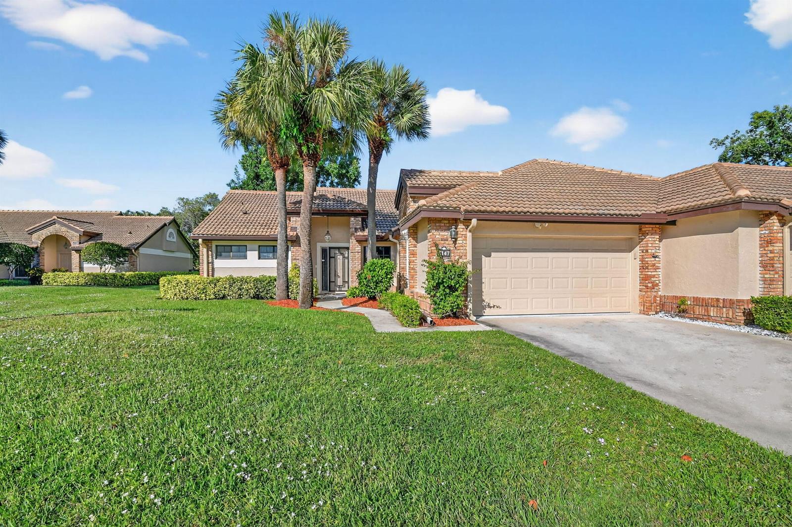 A single-story house with a tiled roof, a two-car garage, and palm trees in front — 7147 Le Chalet Boulevard, Boynton Beach FL 33472, BOYNTON BEACH, FL