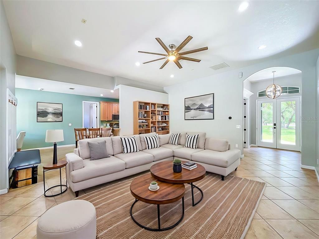 A living room features a sectional sofa, two round coffee tables, and tile flooring — 30115 W THYME AVE, EUSTIS, FL