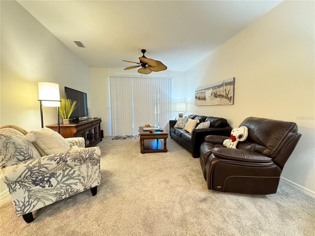 A living room features beige carpet, a ceiling fan, a sofa, a recliner, and furniture — 7212 HAMILTON ROAD UNIT 7212, BRADENTON, FL