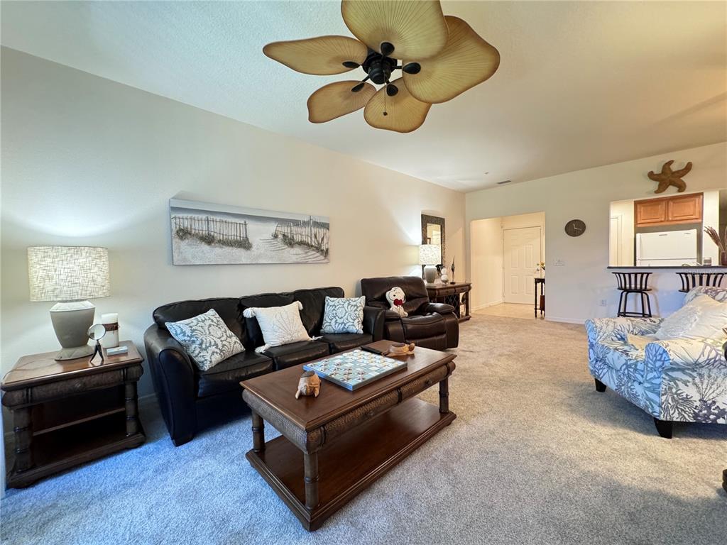 A living room features a dark leather sofa, a wooden coffee table, and a ceiling fan — 7212 HAMILTON ROAD UNIT 7212, BRADENTON, FL