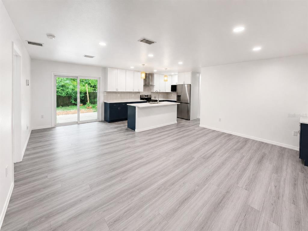 An open-concept kitchen features white upper cabinets, dark lower cabinets, and light wood-look flooring — 4302 NW 21ST DRIVE, GAINESVILLE, FL