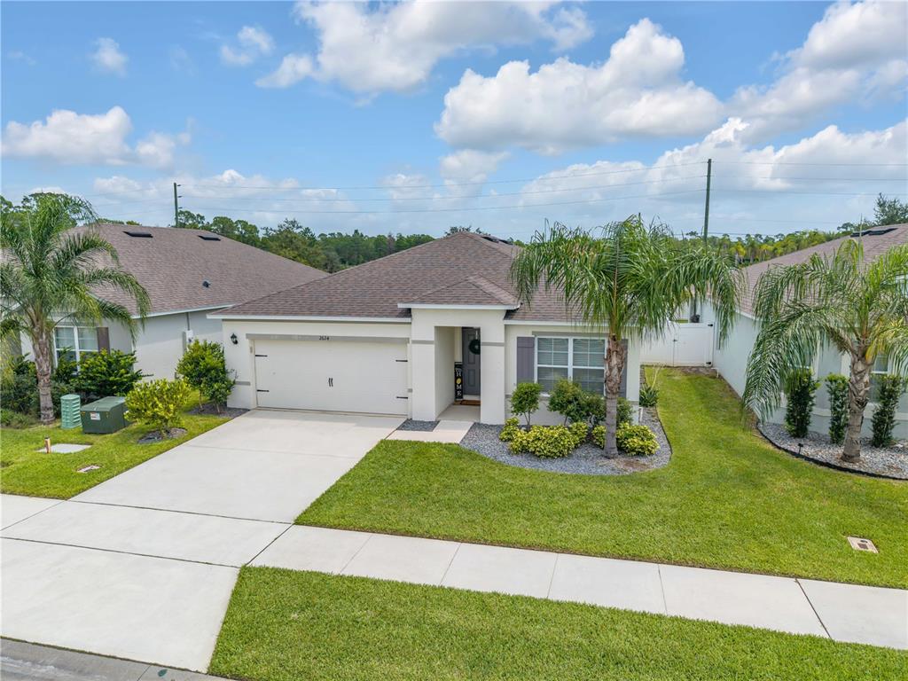 A single-story suburban house with a two-car garage, palm trees, and a concrete driveway — 2624 NEVERLAND DRIVE, NEW SMYRNA BEACH, FL
