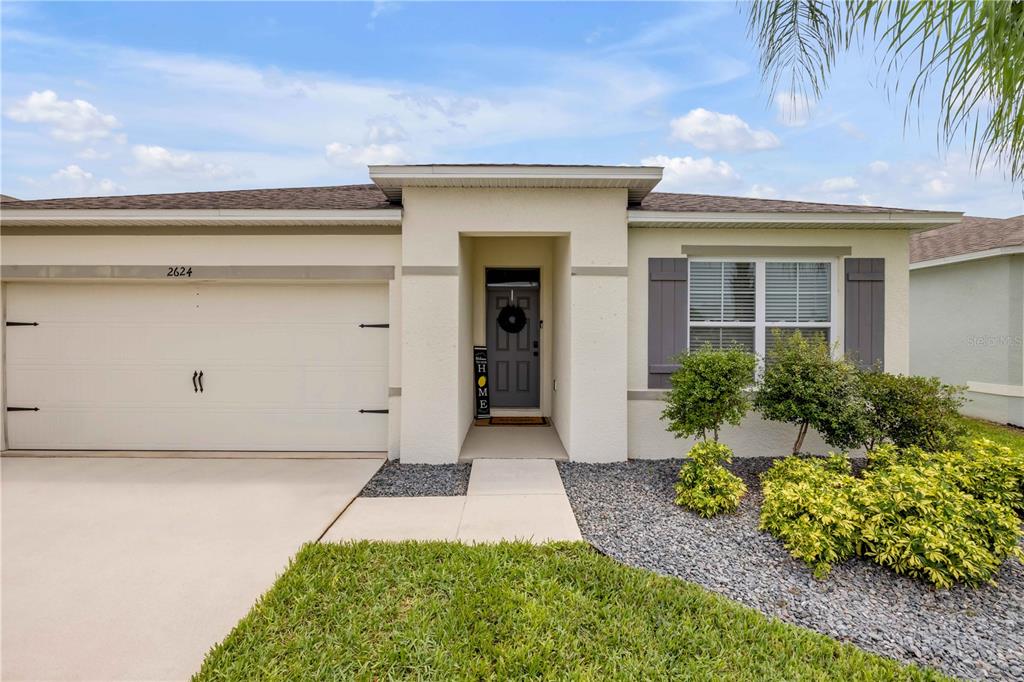A single-story house with a beige stucco exterior, a two-car garage, and a front entryway — 2624 NEVERLAND DRIVE, NEW SMYRNA BEACH, FL