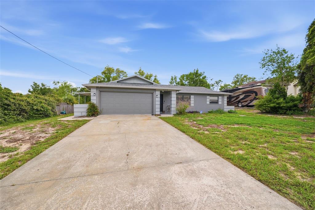 A single-story gray house with a two-car garage and a concrete driveway — 6310 GAINSBORO AVENUE, SPRING HILL, FL