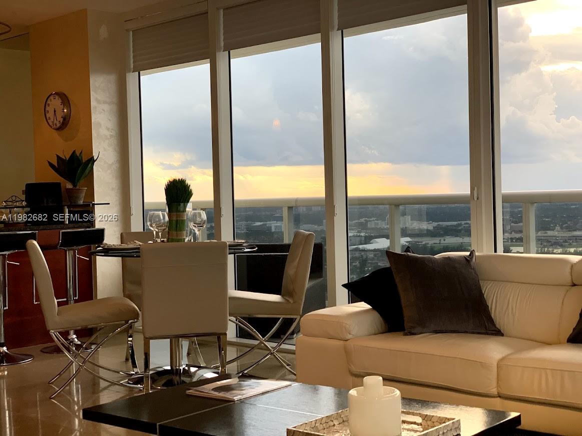 A modern living and dining area features floor-to-ceiling windows with a sunset city view — 1830 S Ocean Dr # 4608, Hallandale Beach FL 33009, HALLANDALE BEACH, FL