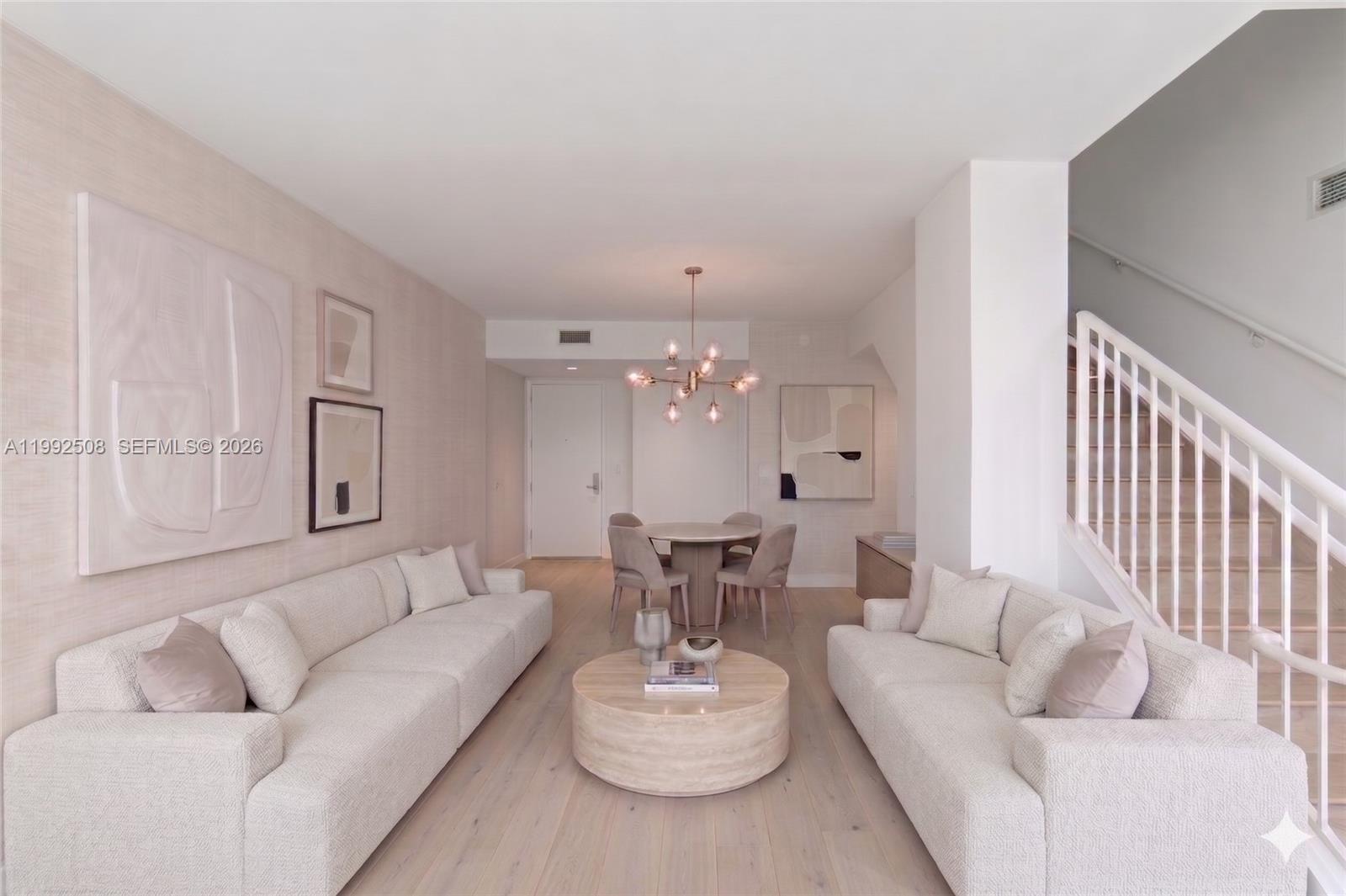 A living and dining area features light-toned furniture, wood flooring, and a staircase — 1395 Brickell Ave # 3407, Miami FL 33131, MIAMI, FL