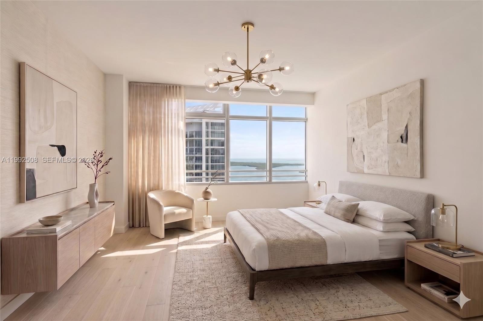 A modern bedroom features a bed, a chandelier, and a large window overlooking the ocean — 1395 Brickell Ave # 3407, Miami FL 33131, MIAMI, FL