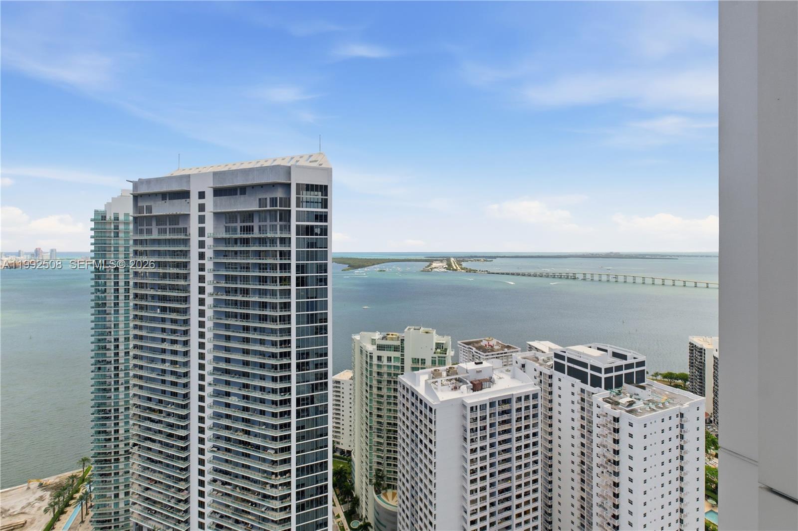 A high-angle view shows several tall residential towers overlooking a bay and bridge — 1395 Brickell Ave # 3407, Miami FL 33131, MIAMI, FL