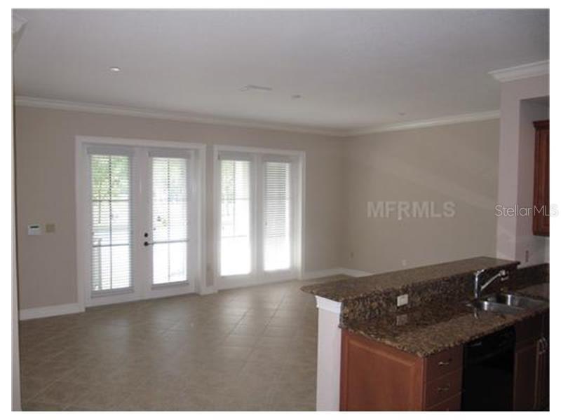 An open living area with tile floors, glass doors, and a kitchen with granite countertops — 619 FRONT STREET UNIT 3104, CELEBRATION, FL
