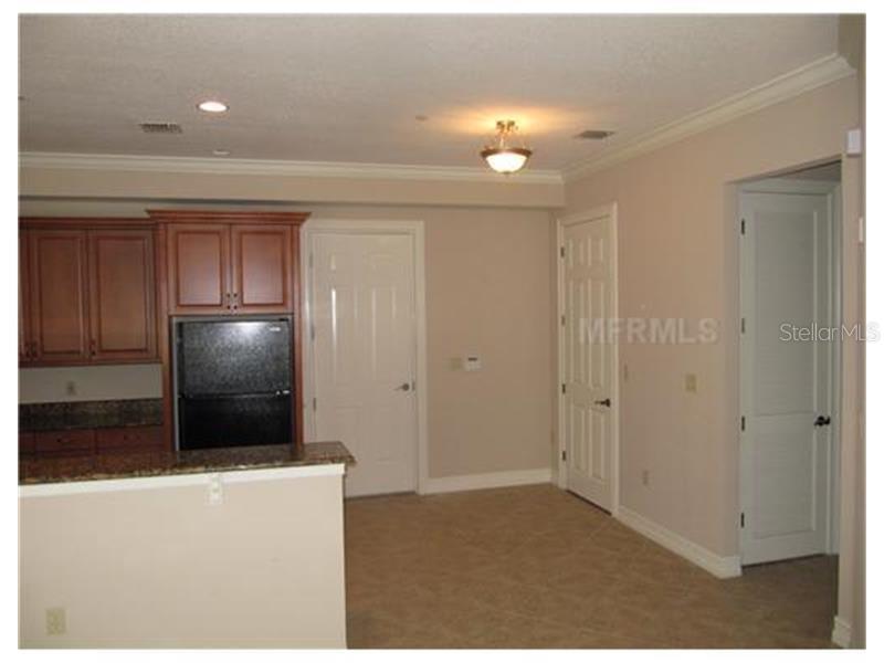 A kitchen with dark wood cabinets, granite countertops, and a black refrigerator — 619 FRONT STREET UNIT 3104, CELEBRATION, FL