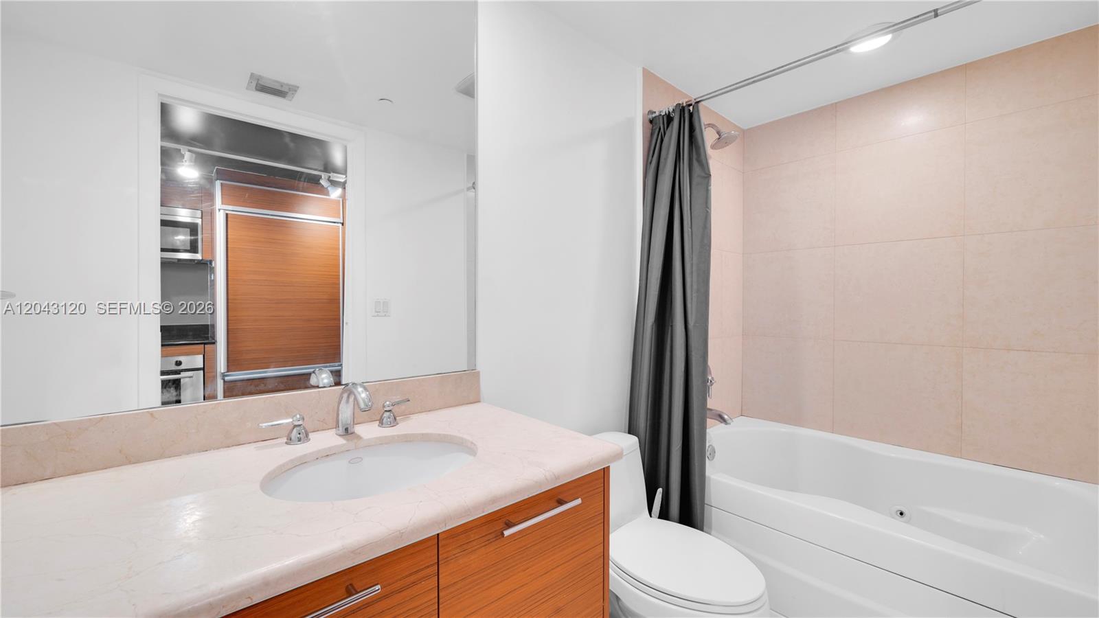 A bathroom features a vanity with a stone countertop, a toilet, and a tiled bathtub — 50 Biscayne Blvd # 4203, Miami FL 33132, MIAMI, FL