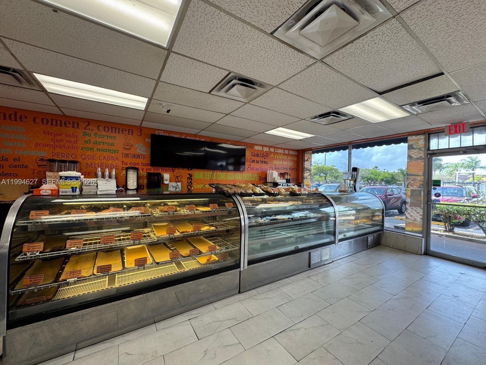 A commercial bakery interior features glass display cases filled with food against an orange wall — 11454 Quail Roost DR, Miami FL 33157, MIAMI, FL