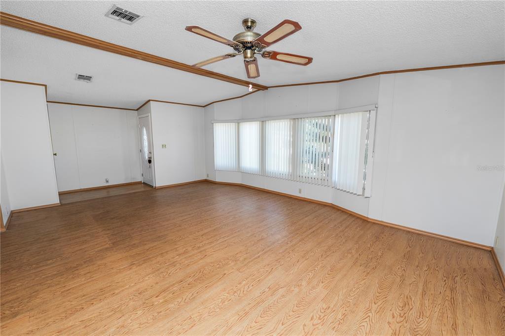 An open-concept living and dining area features wood-look flooring, a ceiling fan, and a pass-through — 1706 FOX HILL DRIVE, LAKELAND, FL