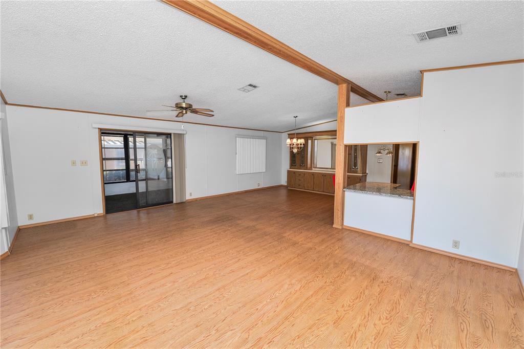 An open-concept living area features light wood-look flooring, white walls, and a ceiling fan — 1706 FOX HILL DRIVE, LAKELAND, FL