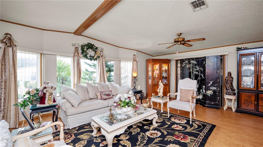 A spacious living room features wood-look flooring, a ceiling fan, and a built-in wooden hutch — 1706 FOX HILL DRIVE, LAKELAND, FL