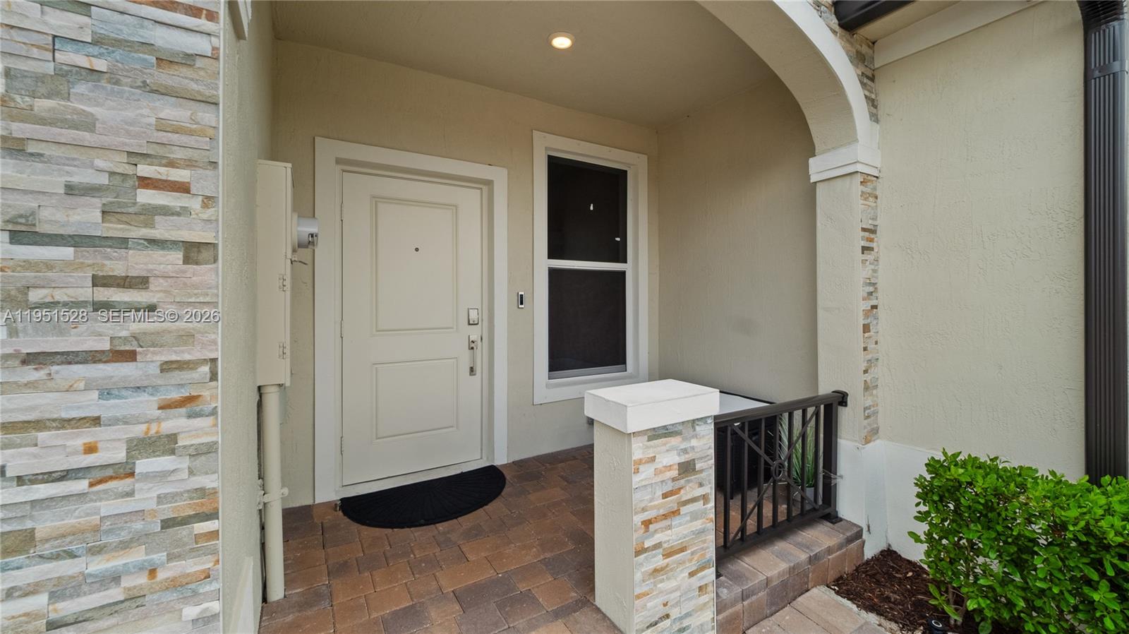 The exterior entrance features a stone-accented wall, a white door, and a paved porch — 5544 NW 27th Pl, Lauderhill FL 33313, LAUDERHILL, FL