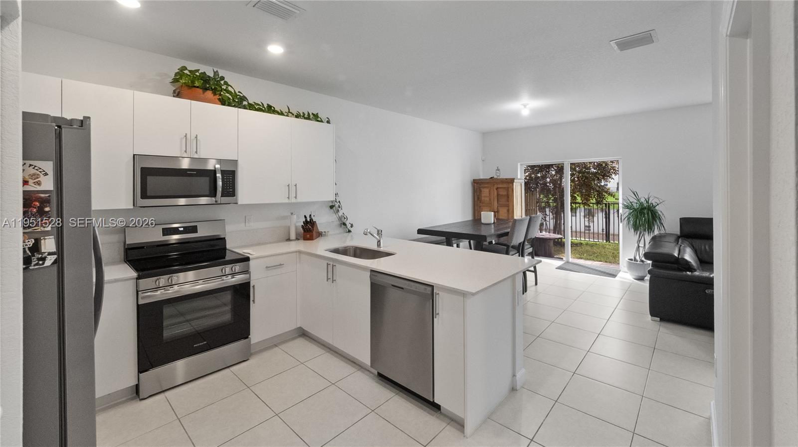 A kitchen with white cabinets and stainless steel appliances opens to a dining area — 5544 NW 27th Pl, Lauderhill FL 33313, LAUDERHILL, FL