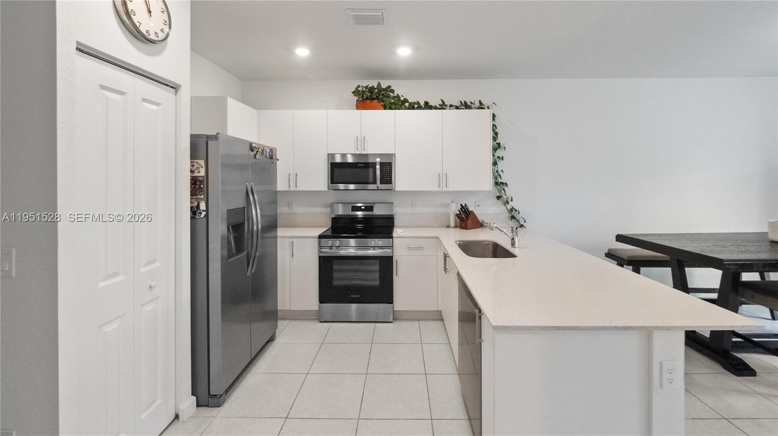 A kitchen features white cabinets, stainless steel appliances, and a quartz-topped island with seating — 5544 NW 27th Pl, Lauderhill FL 33313, LAUDERHILL, FL