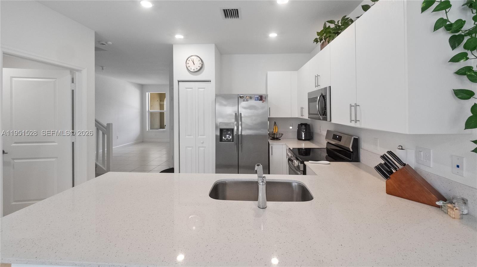 A modern kitchen features white cabinets, stainless steel appliances, and a quartz-topped island sink — 5544 NW 27th Pl, Lauderhill FL 33313, LAUDERHILL, FL