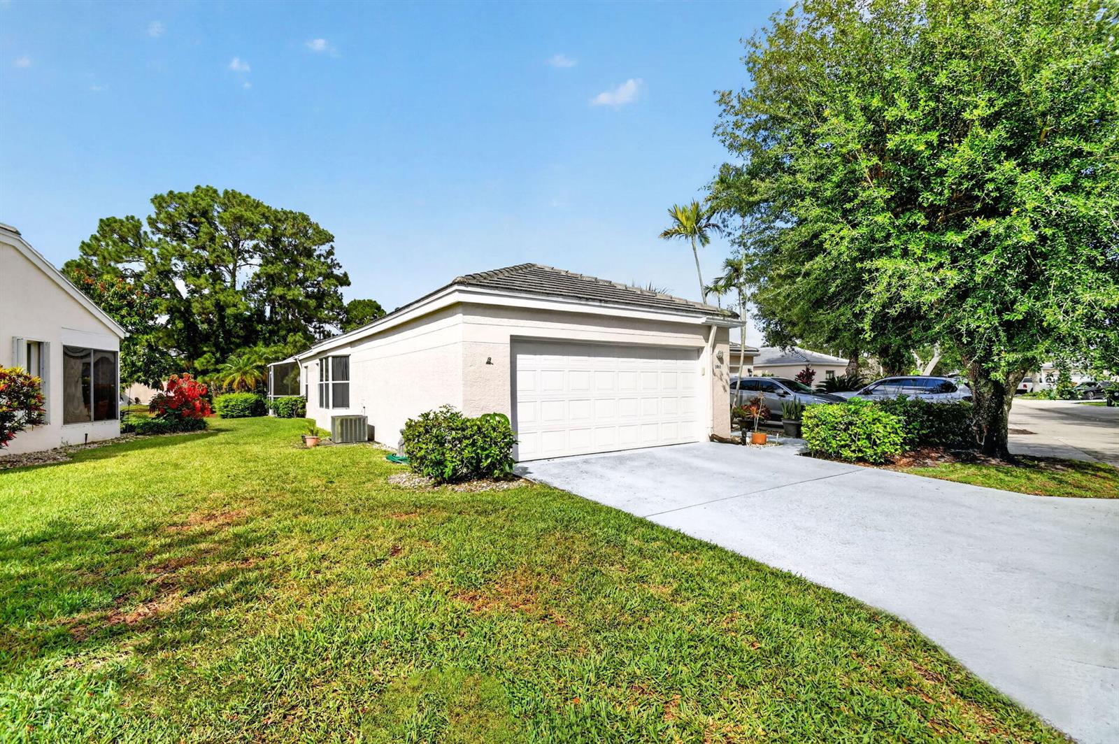 A single-story house with a white garage door, concrete driveway, and green lawn — 1081 Island Manor Drive, FL 33413, FL