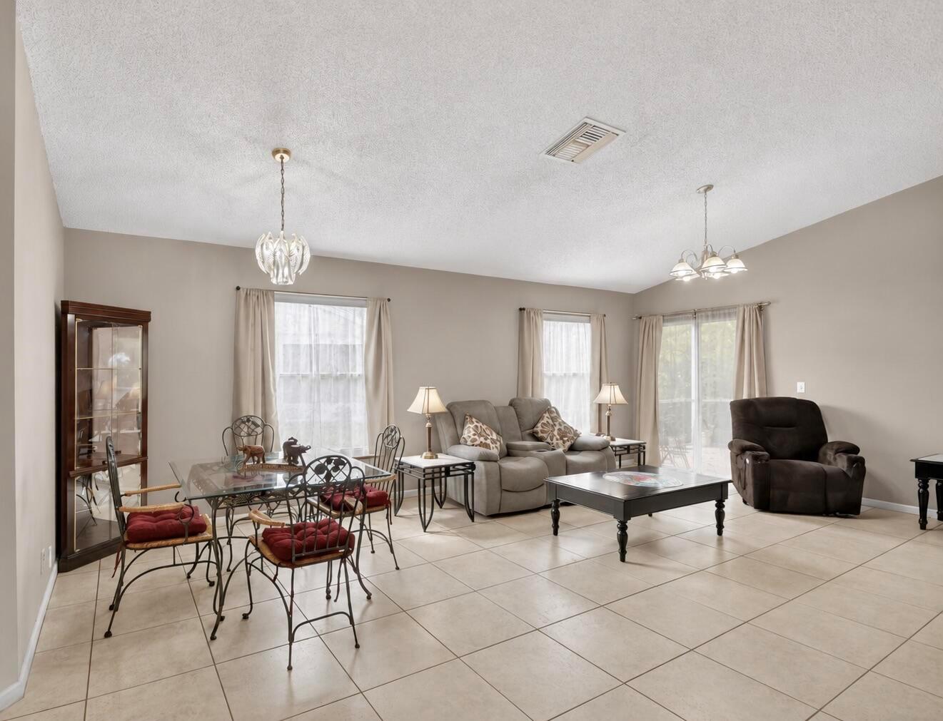 A living and dining room with tile floors, neutral walls, and a vaulted ceiling — 1081 Island Manor Drive, FL 33413, FL