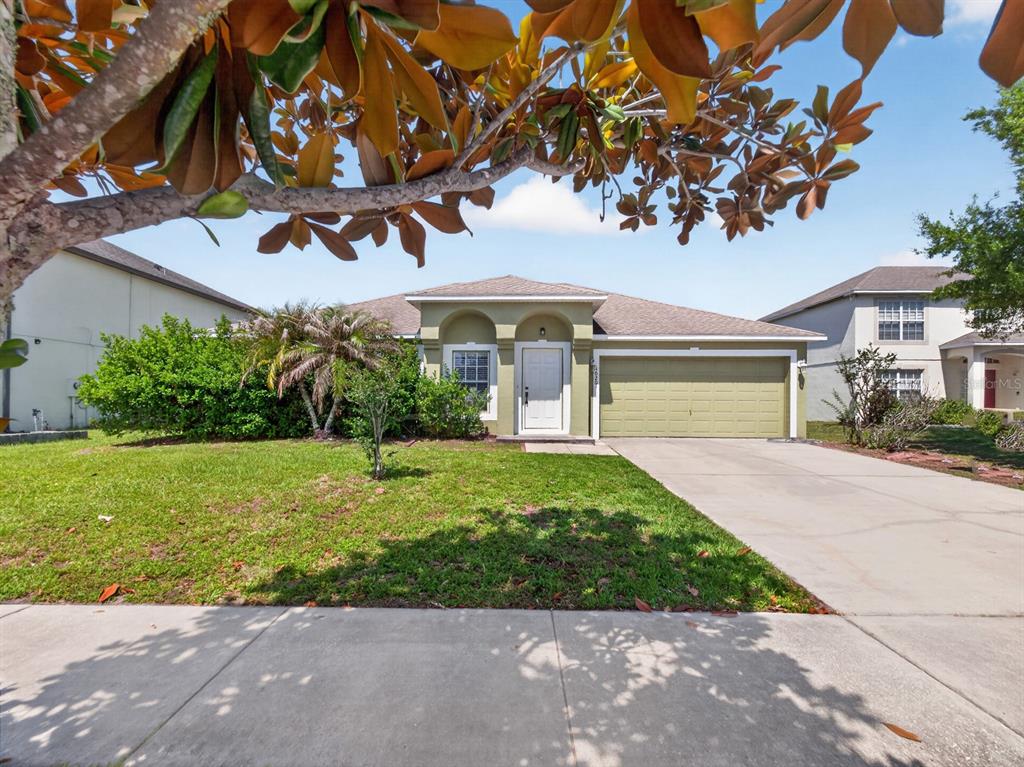 A single-story house with a green exterior, a two-car garage, and a front lawn — 4020 SUNNY DAY WAY, KISSIMMEE, FL