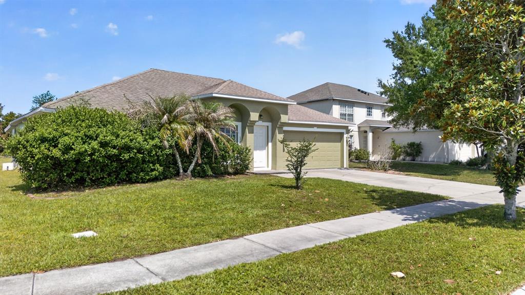 A single-story house with a tan exterior, a two-car garage, and a manicured front lawn — 4020 SUNNY DAY WAY, KISSIMMEE, FL