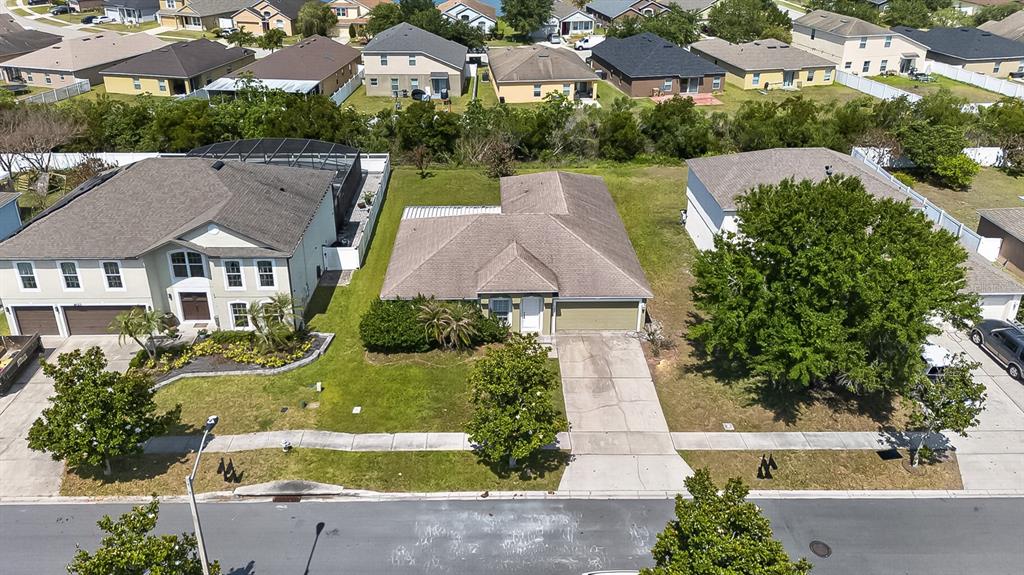 An aerial view shows a single-story house with a tan exterior and a driveway — 4020 SUNNY DAY WAY, KISSIMMEE, FL
