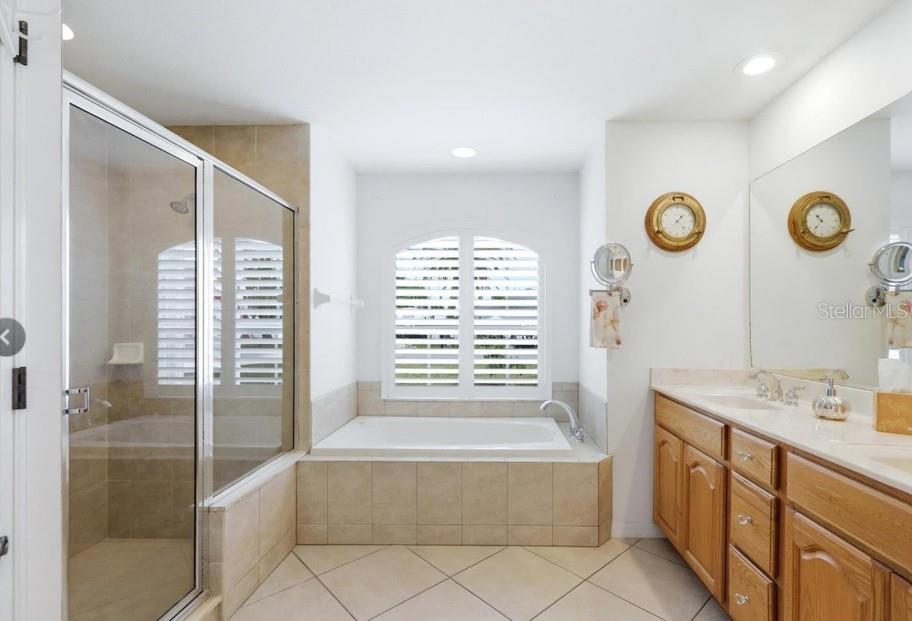 A bathroom features a glass-enclosed shower, a soaking tub under a window, and wooden cabinets — 5948 ORCHIS ROAD, VENICE, FL