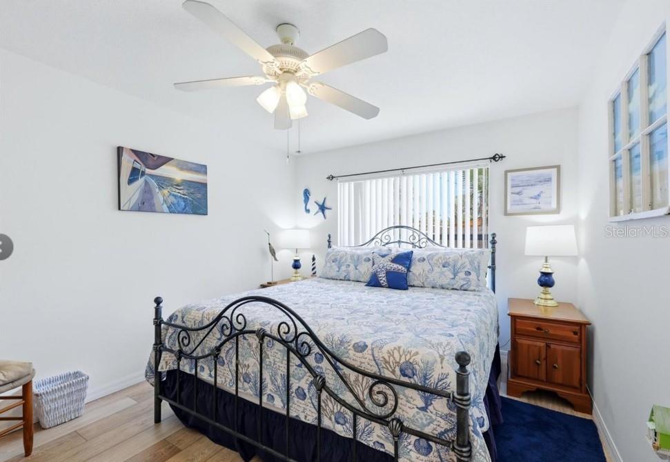A bedroom features a wrought iron bed frame, coastal bedding, and a white ceiling fan — 5948 ORCHIS ROAD, VENICE, FL