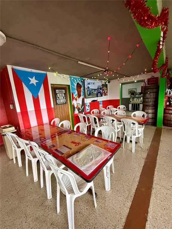 A dining area features tables with white chairs, a Puerto Rican flag, and festive decorations — 149 ROUTE UNIT KM 18.3, CIALES, PR