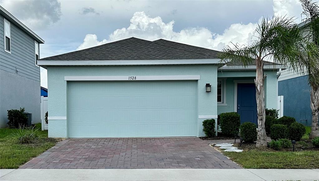 A light blue single-story house with a two-car garage and a paved driveway — 1528 EUCALYPTUS WAY, DAVENPORT, FL