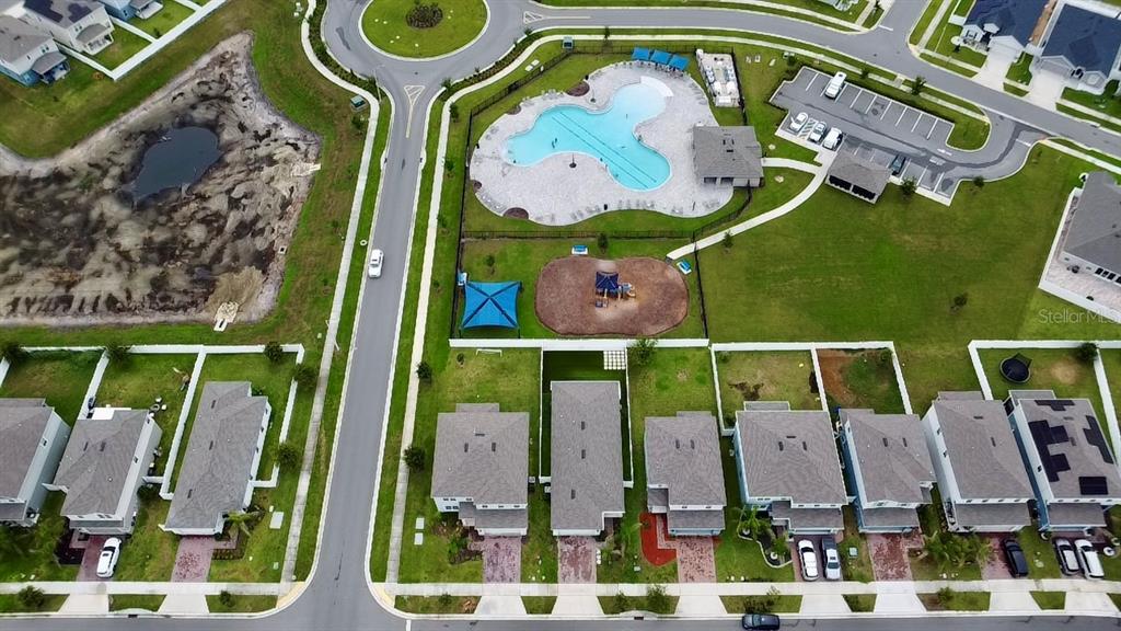 An aerial view shows a residential neighborhood with a community pool, playground, and houses — 1528 EUCALYPTUS WAY, DAVENPORT, FL