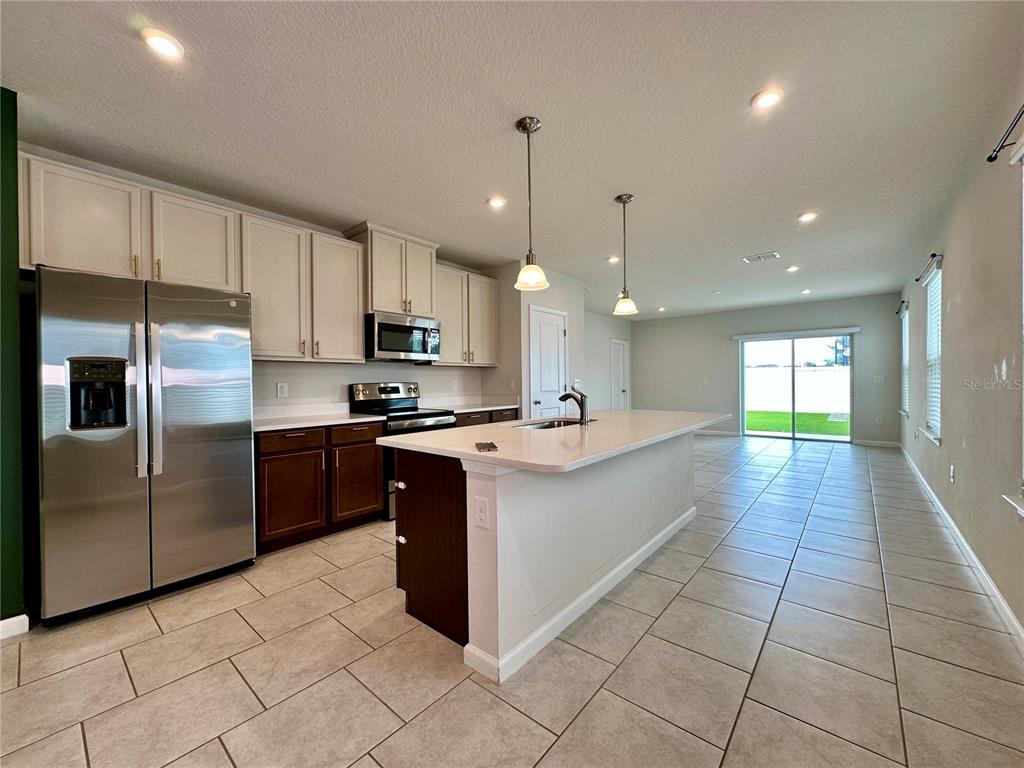 A kitchen with white upper cabinets, dark lower cabinets, a center island, and tile flooring — 1528 EUCALYPTUS WAY, DAVENPORT, FL