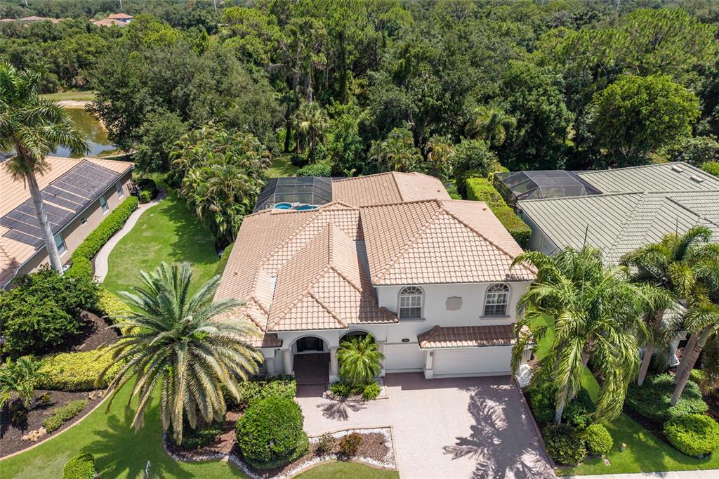 An aerial view shows a two-story house with a tiled roof, pool cage, and palm trees — 7110 GRASSLAND COURT, SARASOTA, FL