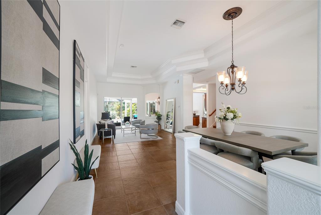 A dining area and living room with tile floors, white walls, and a tray ceiling — 7110 GRASSLAND COURT, SARASOTA, FL