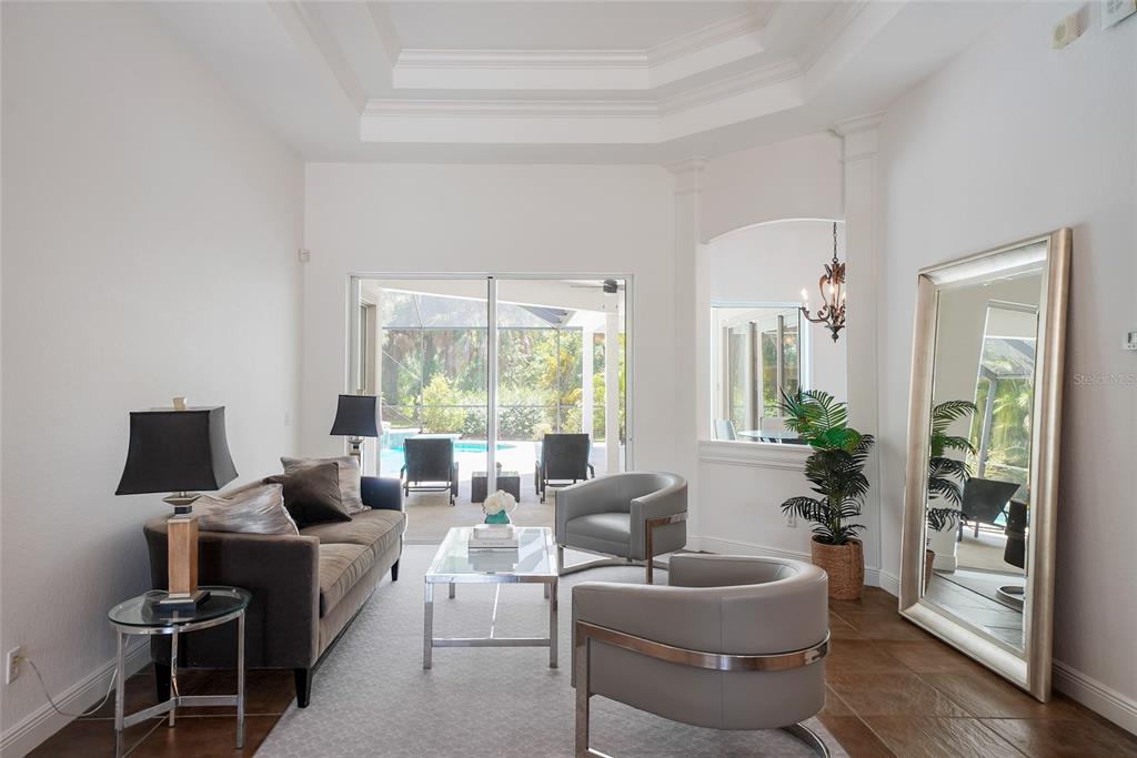 A living room features a sofa, two armchairs, a glass coffee table, and a large mirror — 7110 GRASSLAND COURT, SARASOTA, FL