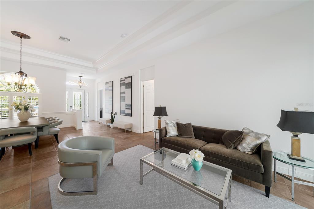 A living and dining area with tile floors, a brown sofa, and a glass coffee table — 7110 GRASSLAND COURT, SARASOTA, FL