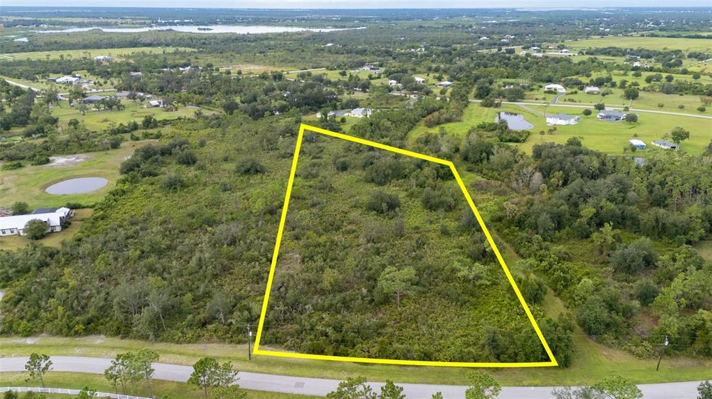 An aerial view shows a vacant, wooded lot outlined in yellow along a paved road — 5700 BLACKJACK COURT S, PUNTA GORDA, FL