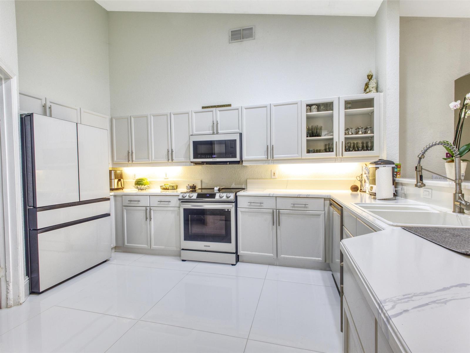 A modern kitchen features white cabinetry, stainless steel appliances, and white marble-look countertops — 6660 Conch Court, Boynton Beach FL 33437, BOYNTON BEACH, FL