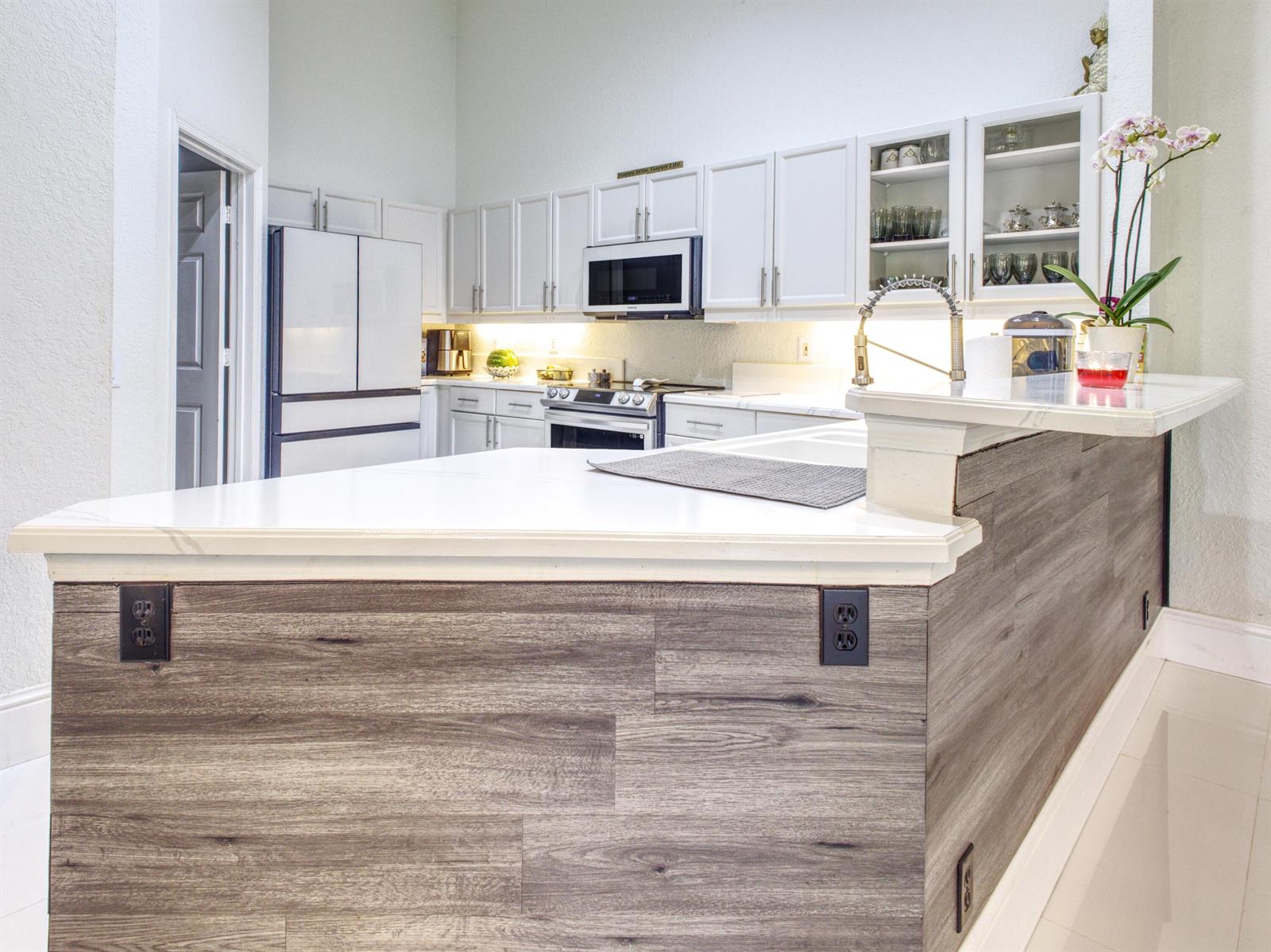 A kitchen features white cabinetry, a wood-paneled island with a white countertop, and stainless appliances — 6660 Conch Court, Boynton Beach FL 33437, BOYNTON BEACH, FL
