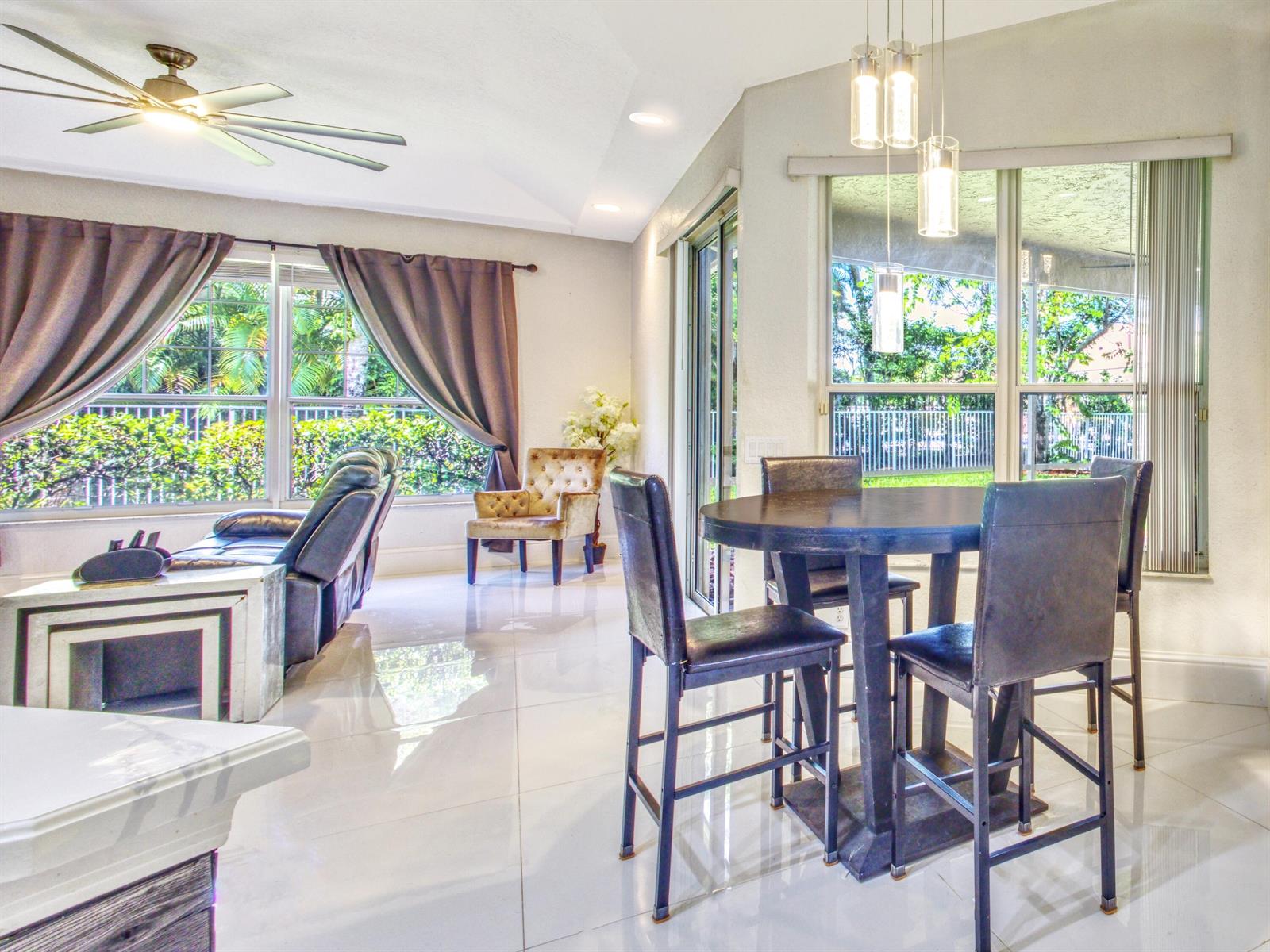 A bright dining area and living room with tile floors, a ceiling fan, and windows — 6660 Conch Court, Boynton Beach FL 33437, BOYNTON BEACH, FL